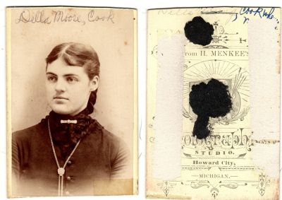 Della Phoebe Moore Cook

This cut CdV Photograph states: "Della Moore Cook"

The Photographers name is "Menkee's Photograph Studio", Howard City, Michigan.
